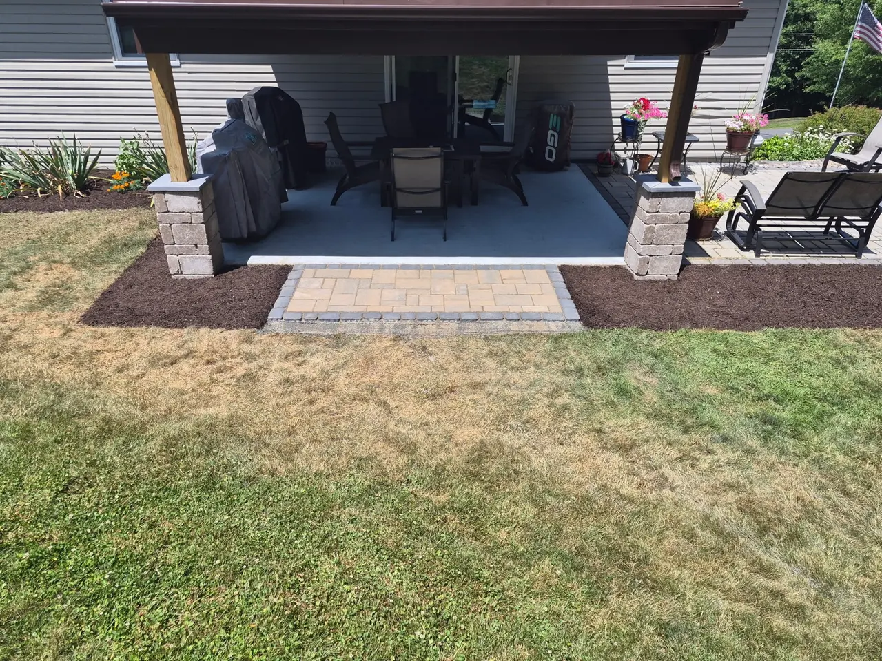 Paver landing connecting a covered seating area to the lawn