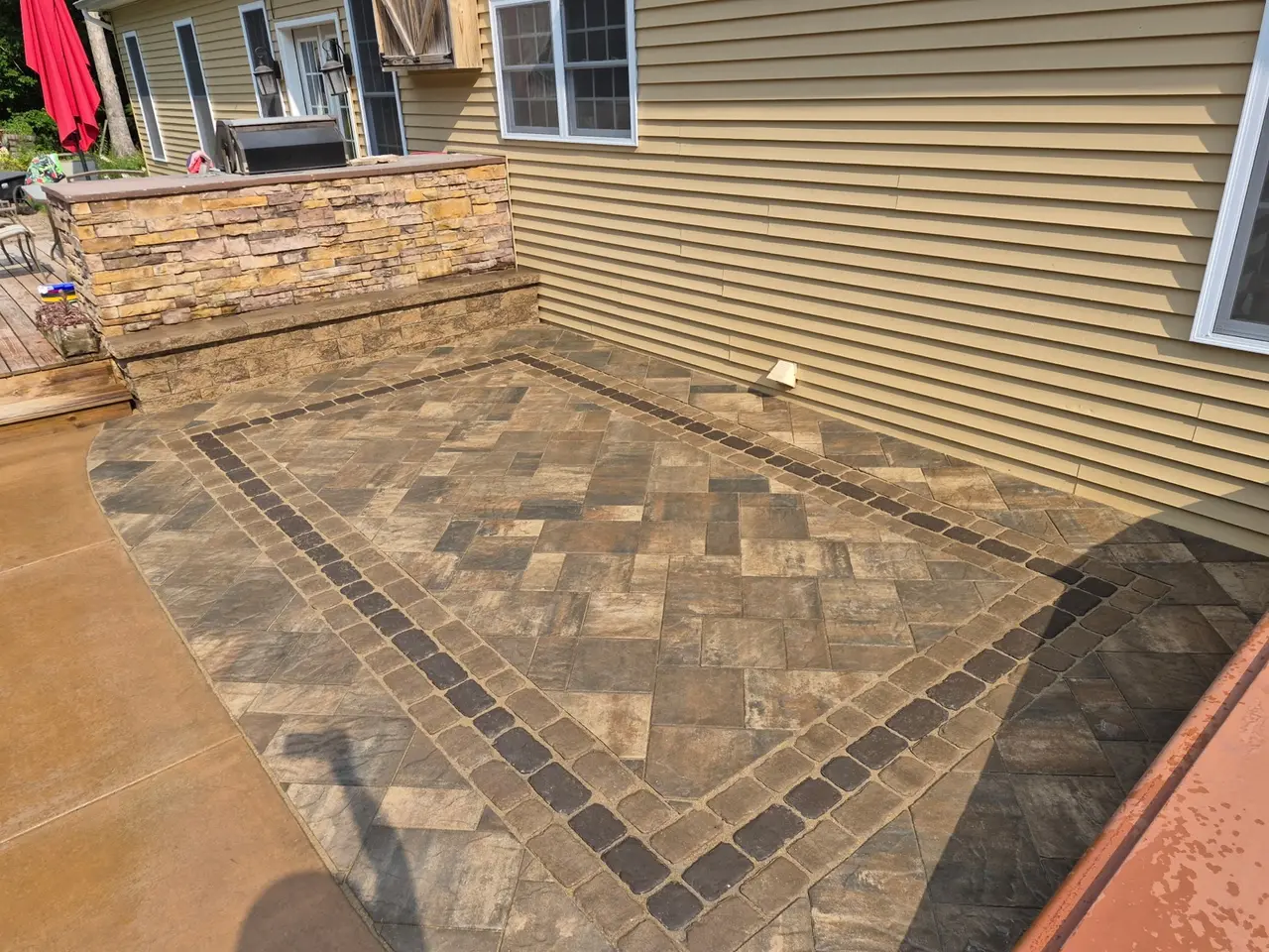 Curved patio edge and dark inset border around patterned pavers