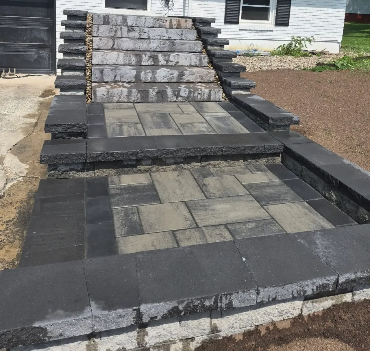 Tiered block walls framing stone steps and paver landings